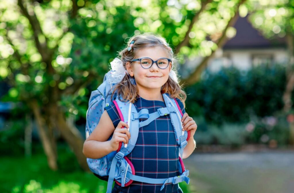 A young child wearing glasses heading off to school after having their routine eye exam.