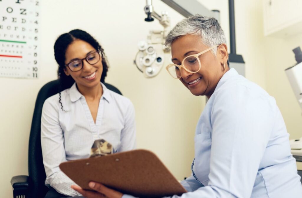 An optometrist holding a clipboard discusses dry eye treatment options with their patient.