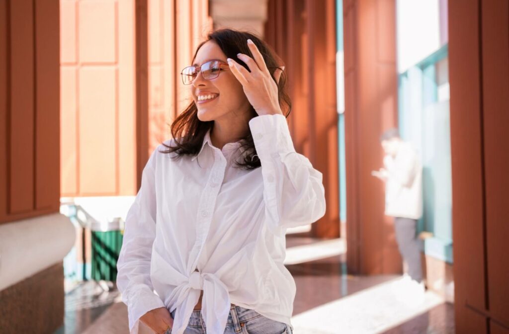 A young woman wearing migraine glasses smiles, showing signs of comfort.