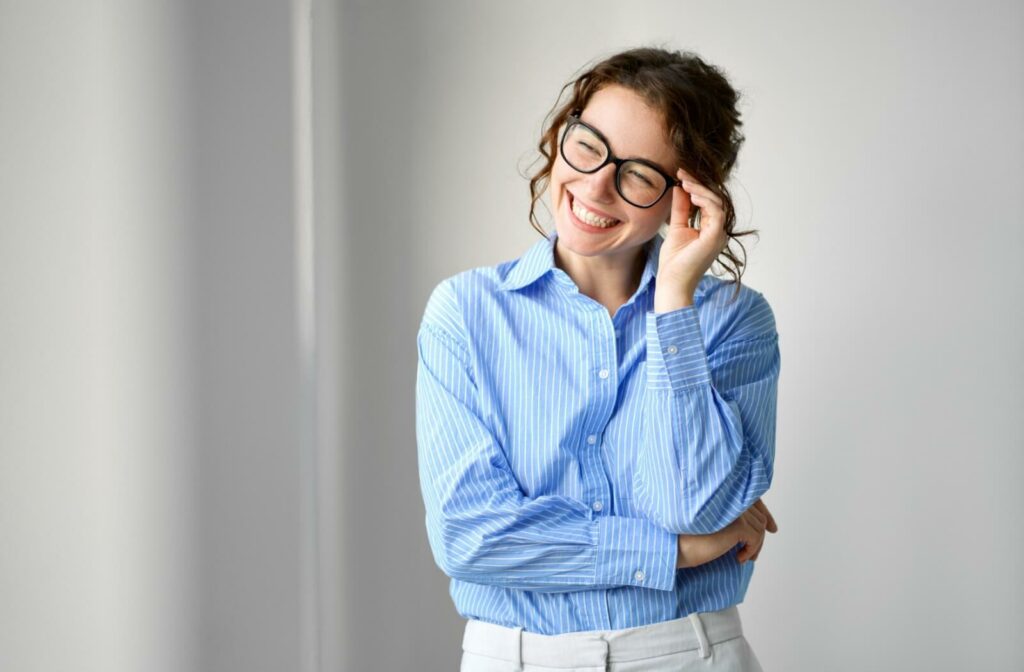 Smiling adult wearing Neurolens glasses and a blue striped shirt standing in a bright room