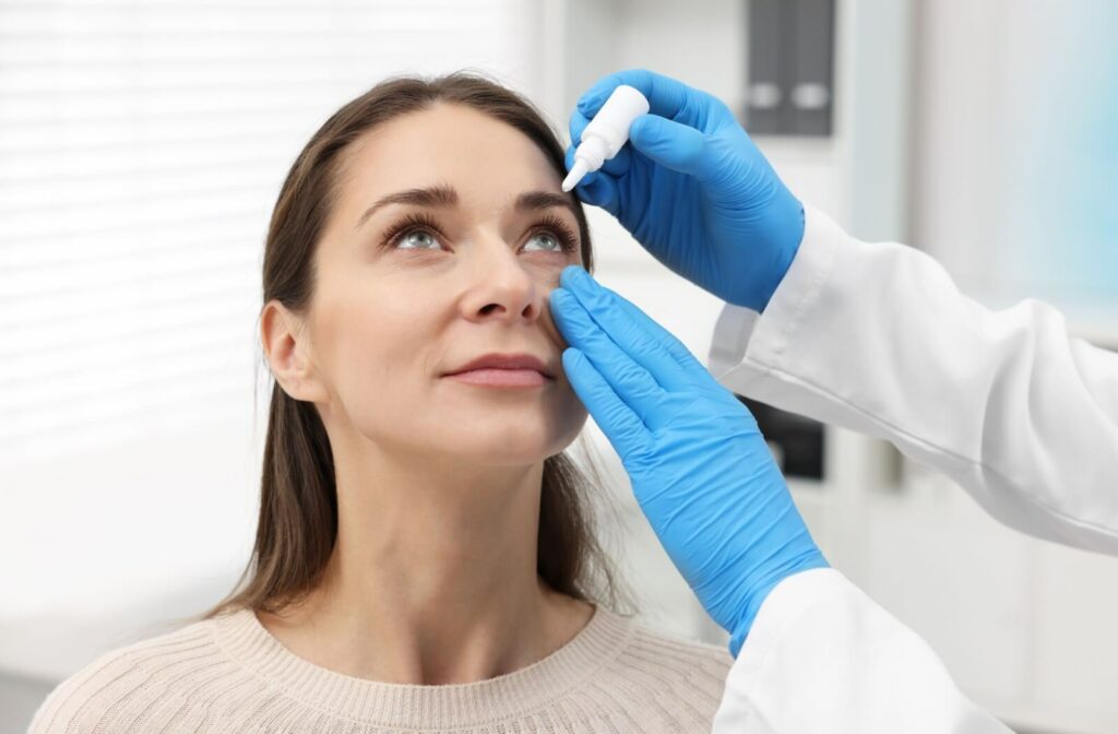 An optometrist applying eye drops to a patient.
